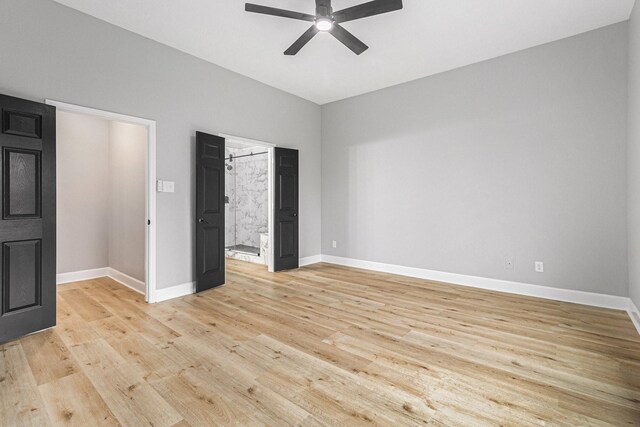 unfurnished bedroom with light wood-style flooring, baseboards, and ensuite bathroom
