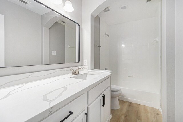 bathroom featuring wood finished floors, shower / bathing tub combination, vanity, toilet, and visible vents