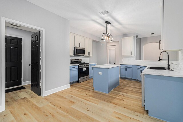 kitchen with white cabinets, appliances with stainless steel finishes, a sink, and a kitchen island