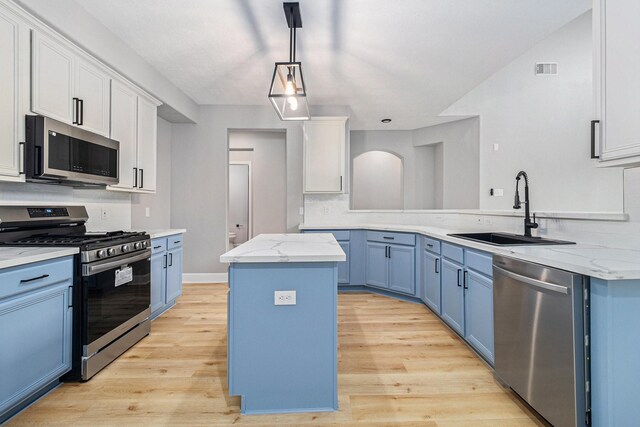 kitchen with blue cabinets, stainless steel appliances, light wood-style flooring, and a sink