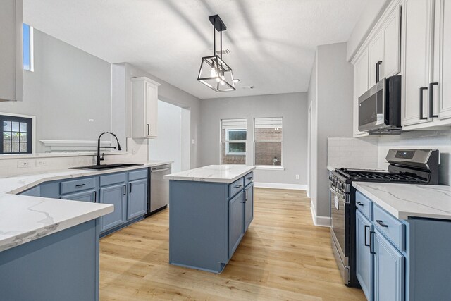 kitchen with blue cabinets, stainless steel appliances, a center island, and a sink