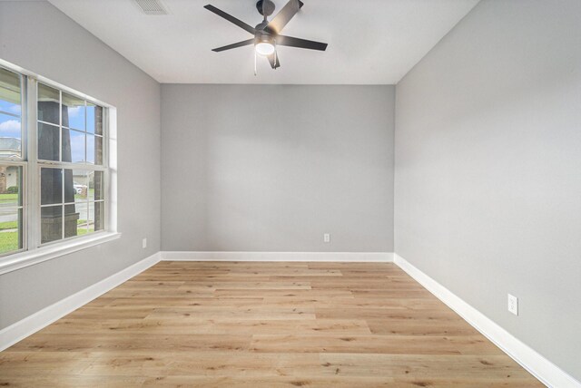 empty room featuring light wood-type flooring, plenty of natural light, a ceiling fan, and baseboards