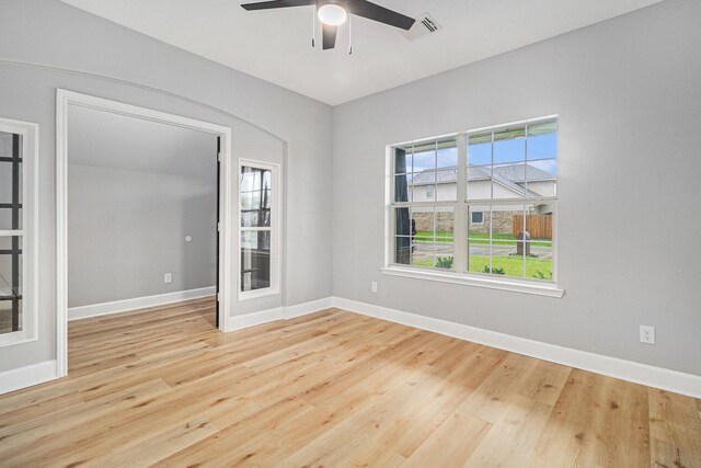 spare room with wood finished floors, visible vents, a ceiling fan, and baseboards