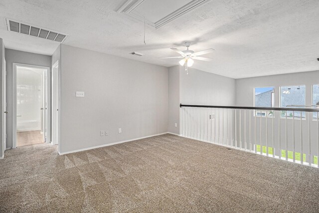 spare room featuring attic access, a textured ceiling, visible vents, and carpet flooring