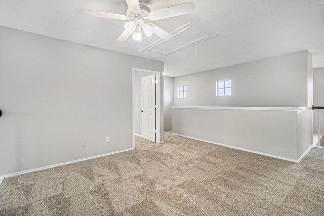 spare room with attic access, baseboards, a ceiling fan, and carpet flooring