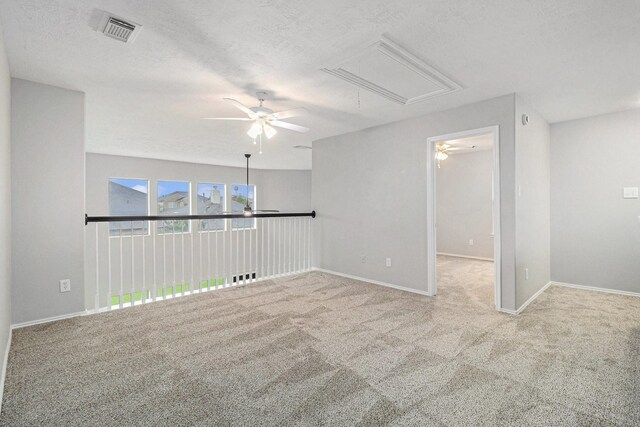 spare room with visible vents, attic access, a textured ceiling, carpet flooring, and ceiling fan