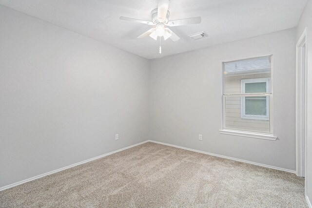 carpeted spare room featuring baseboards, a ceiling fan, and visible vents