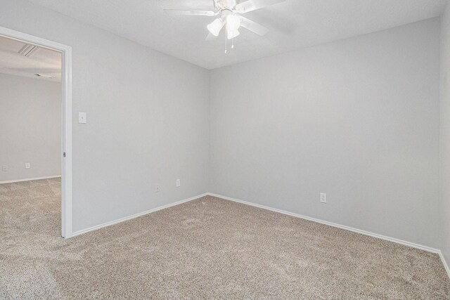 carpeted spare room with a ceiling fan and baseboards
