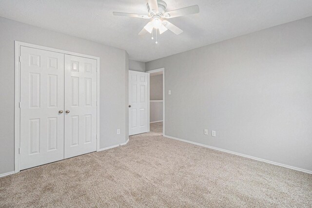 unfurnished bedroom with baseboards, carpet flooring, a closet, and ceiling fan