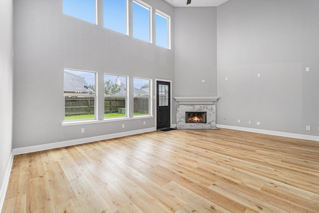 unfurnished living room with a fireplace, wood finished floors, a high ceiling, and baseboards