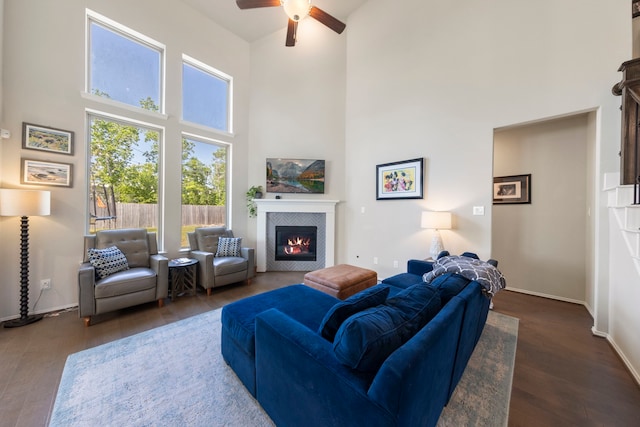 32055 August Woods Way, Conroe, TX 77385 - living area with a ceiling fan, a towering ceiling, a tiled fireplace, baseboards, and dark wood-type flooring
