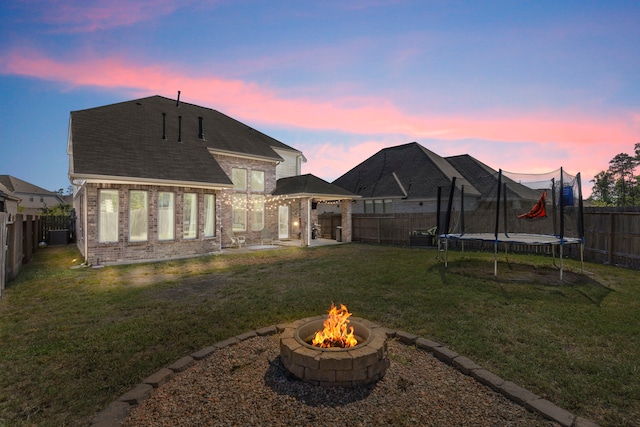 32055 August Woods Way, Conroe, TX 77385 - back of house featuring a gazebo, brick siding, a trampoline, a lawn, and an outdoor fire pit