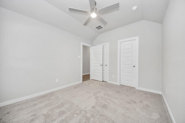 unfurnished bedroom featuring light colored carpet, lofted ceiling, visible vents, and baseboards