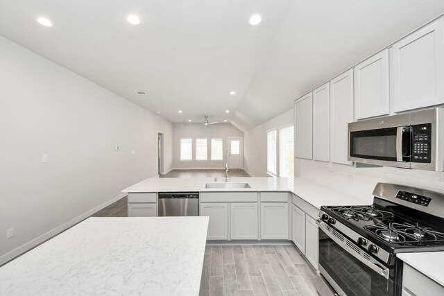 kitchen with vaulted ceiling, a sink, ceiling fan, stainless steel appliances, and light countertops