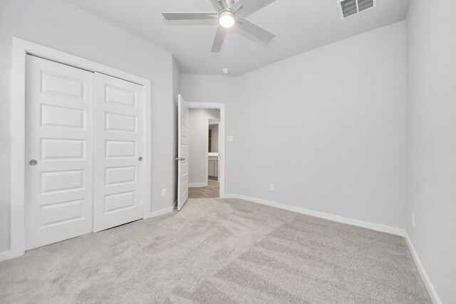 unfurnished bedroom with light carpet, baseboards, visible vents, a closet, and ceiling fan