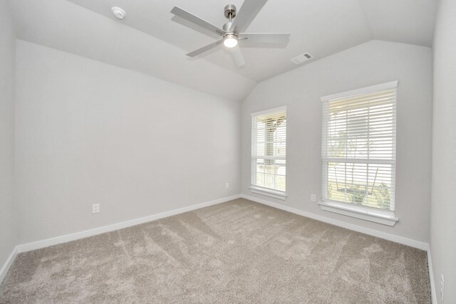 carpeted empty room featuring ceiling fan, lofted ceiling, visible vents, and baseboards