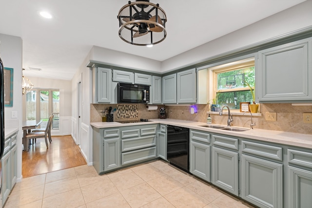 kitchen with a sink, black appliances, light countertops, a notable chandelier, and gray cabinetry