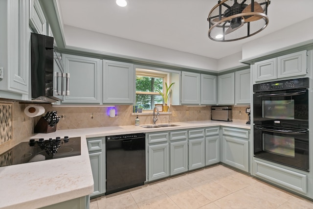 kitchen featuring a sink, decorative backsplash, black appliances, light countertops, and light tile patterned floors