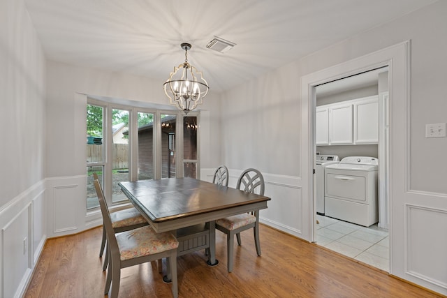 dining area with an inviting chandelier, visible vents, a decorative wall, washing machine and clothes dryer, and wainscoting