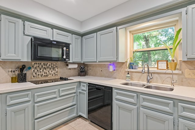 kitchen featuring tasteful backsplash, a sink, black appliances, light tile patterned floors, and light countertops