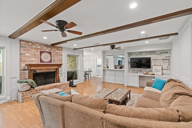 living room with visible vents, beamed ceiling, light wood-type flooring, a decorative wall, and ceiling fan
