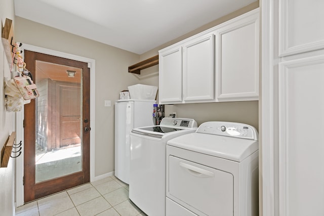 washroom with baseboards, cabinet space, washer and clothes dryer, and light tile patterned floors