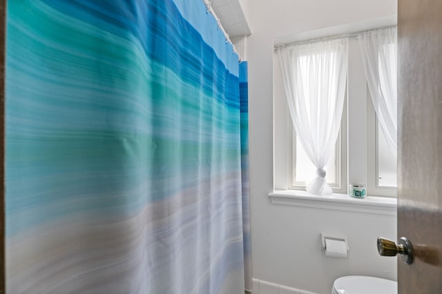 bathroom with baseboards, toilet, and a shower with shower curtain