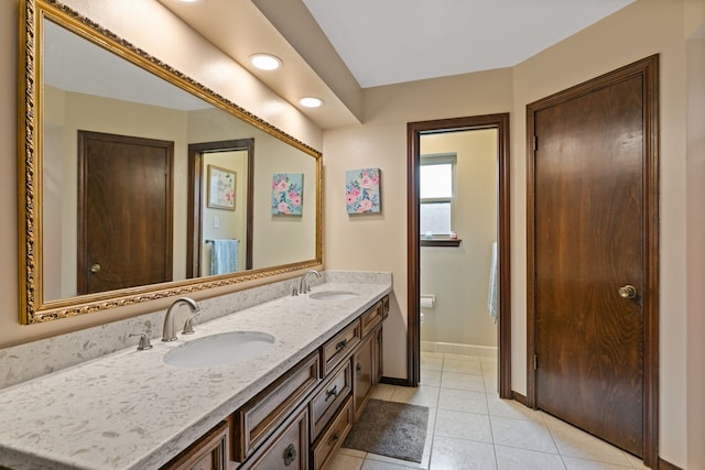 full bathroom with baseboards, tile patterned flooring, a sink, and double vanity