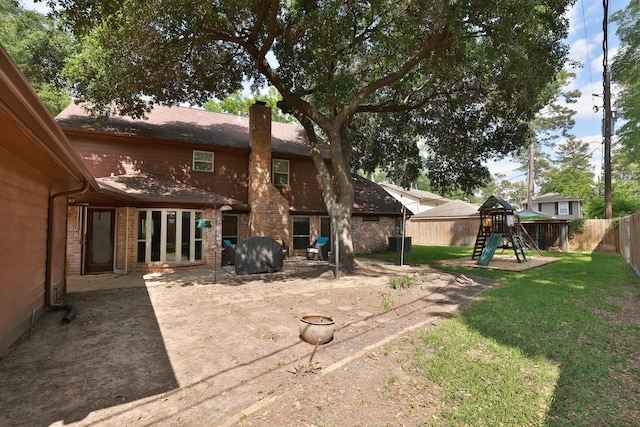rear view of property featuring a fenced backyard, a playground, a chimney, brick siding, and a yard