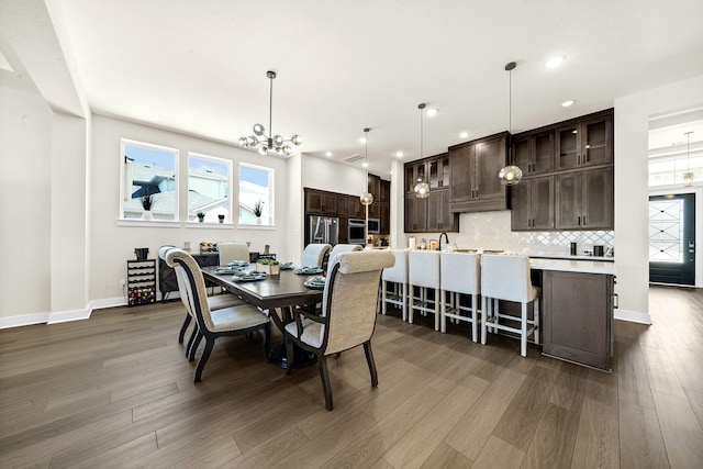 dining space with dark wood-type flooring, recessed lighting, baseboards, and a chandelier