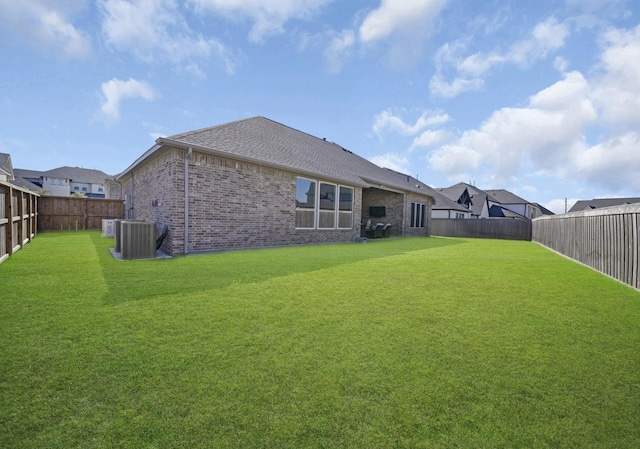back of house featuring a lawn, brick siding, central AC, and a fenced backyard