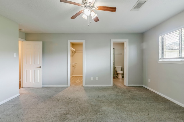 unfurnished bedroom featuring carpet floors, baseboards, a walk in closet, and visible vents