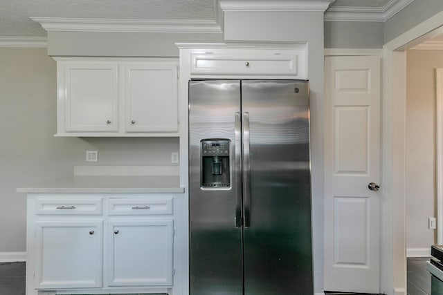 kitchen with light countertops, white cabinetry, crown molding, and stainless steel fridge