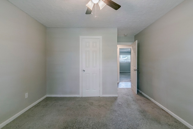 unfurnished bedroom with carpet flooring, a textured ceiling, and baseboards
