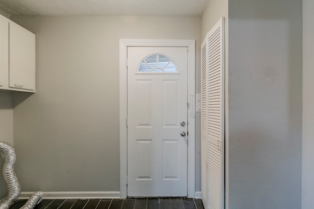 doorway with dark wood-type flooring and baseboards