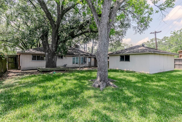 rear view of property with brick siding, fence, and a yard