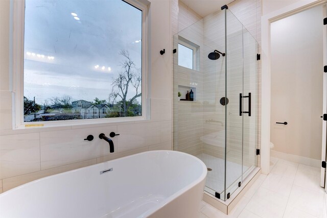 bathroom with a freestanding tub, tile patterned floors, a stall shower, and toilet