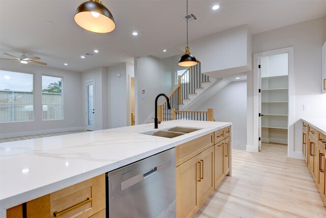 kitchen with dishwasher, a sink, light wood-style floors, light stone countertops, and ceiling fan