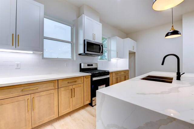 kitchen with light stone counters, decorative backsplash, stainless steel appliances, and a sink