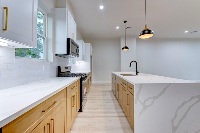 kitchen with stainless steel appliances, a sink, light wood-type flooring, recessed lighting, and backsplash