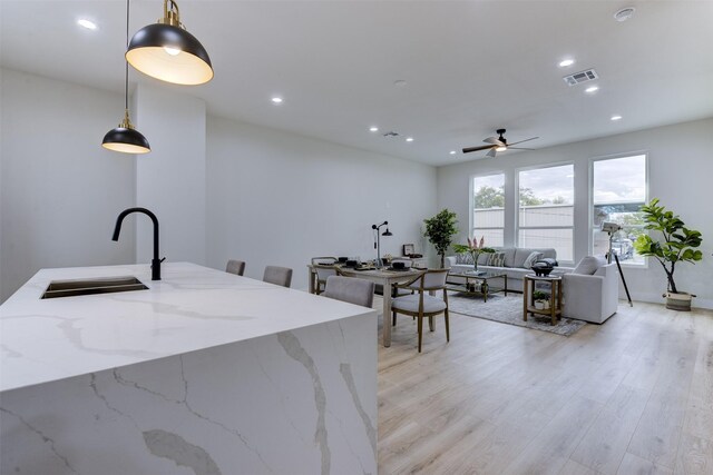kitchen with a sink, visible vents, recessed lighting, light wood-style floors, and hanging light fixtures