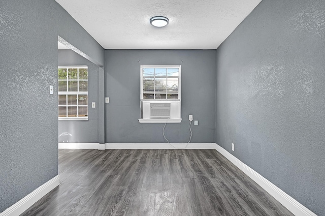 interior space with baseboards, a textured wall, wood finished floors, and a wealth of natural light