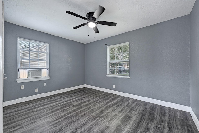 empty room with dark wood-style flooring, cooling unit, a textured ceiling, a ceiling fan, and baseboards