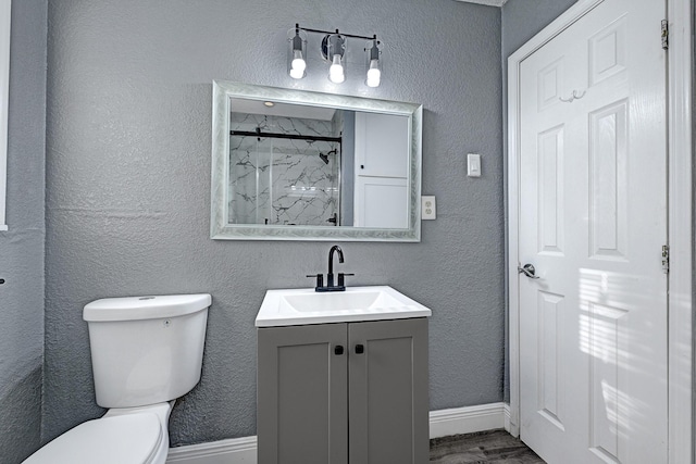 full bathroom featuring walk in shower, wood finished floors, vanity, baseboards, and toilet