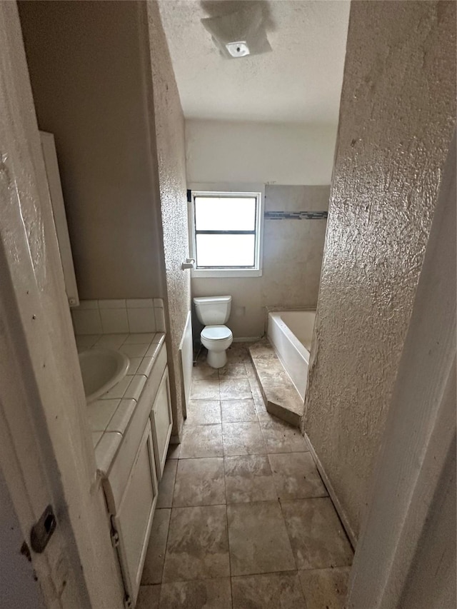 2038 Norfolk St Unit A, Houston, TX 77098 - bathroom with a tub to relax in, a textured wall, toilet, and vanity