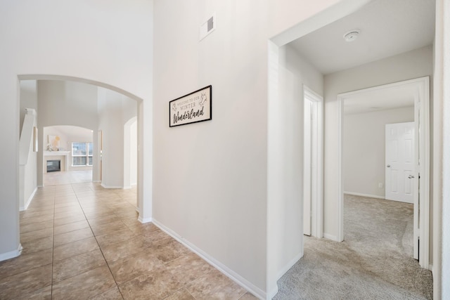 hallway featuring baseboards, visible vents, and arched walkways