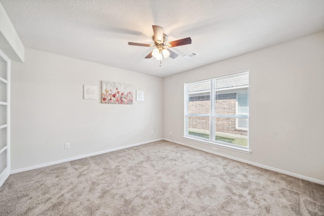 carpeted spare room with ceiling fan, baseboards, a textured ceiling, and visible vents