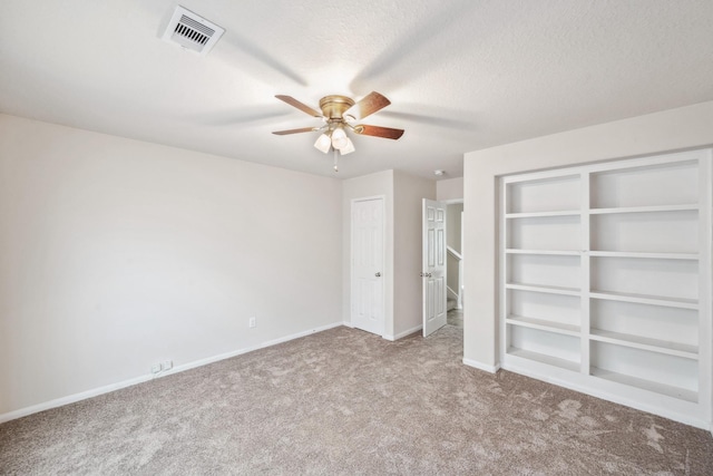 unfurnished bedroom with baseboards, a ceiling fan, visible vents, and carpet
