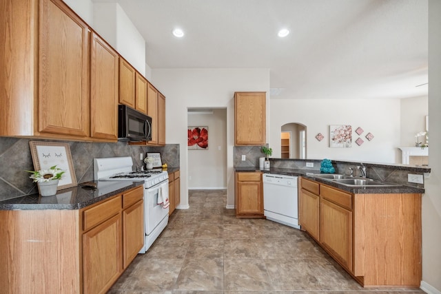 kitchen with a sink, arched walkways, white appliances, a peninsula, and tasteful backsplash