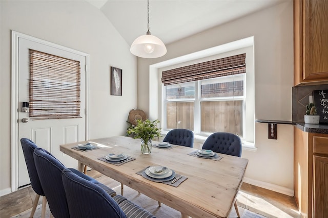dining area featuring lofted ceiling and baseboards